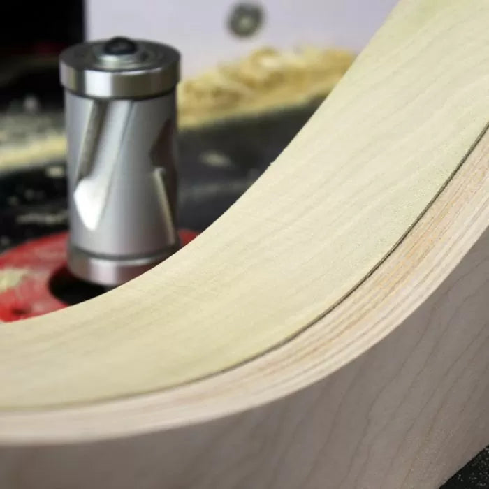 Carbide spiral router bit shaping smooth curved wood edge on a router table