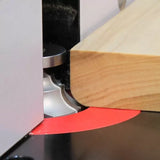 Close-up of woodworking router bit shaping edge of wooden board on router table