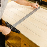Woodworker using a precision T-square to mark lines on a plywood sheet
