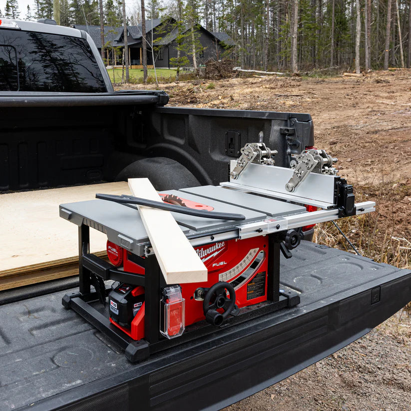Portable table saw with rip fence and wood board on truck bed at outdoor jobsite