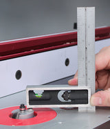 Hand holding a precision square and level to measure a router bit on a router table.