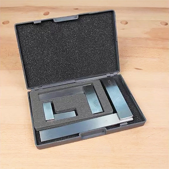 Set of precision steel woodworking squares in a foam-lined case on a workbench