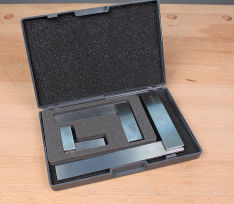 Set of steel woodworking squares and rule in foam-lined case on workbench
