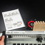 Dovetail jig setup with router table, spiral-bound manual, and wood joinery guide.