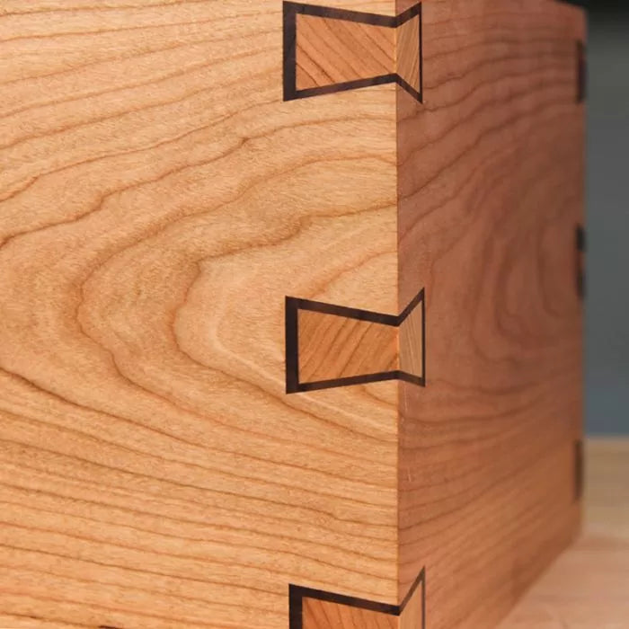 Close-up of a wooden box corner with precise bow tie inlay joints, woodworking detail