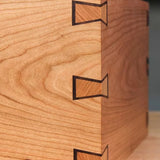 Close-up of a wooden box corner with precise bow tie inlay joints, woodworking detail