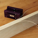Double edge trimmer tool on wood surface with wood edge banding strip curling off