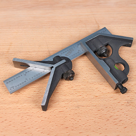 Combination square set with metal ruler and adjustable head on a wooden surface, woodworking tool
