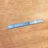 Metal ruler with inch and metric markings on a wooden workbench for woodworking measurement