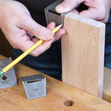 Woodworker marking dovetail joints on a wooden board using a metal dovetail marking jig.
