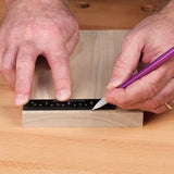 Marking a wooden board with a ruler and pencil on a woodworking bench