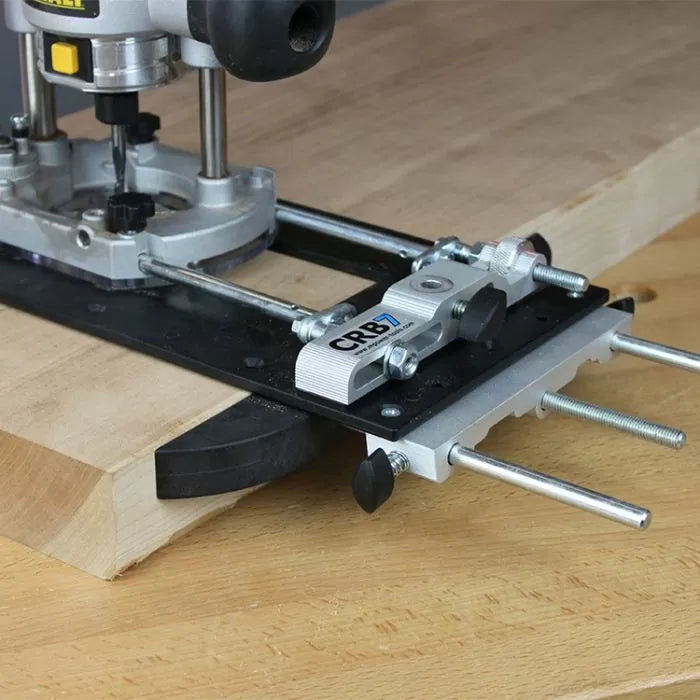 Woodworking router with precision edge guide attachment on wood board
