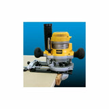 Woodworking router with guide fence cutting wood edge on a workshop table