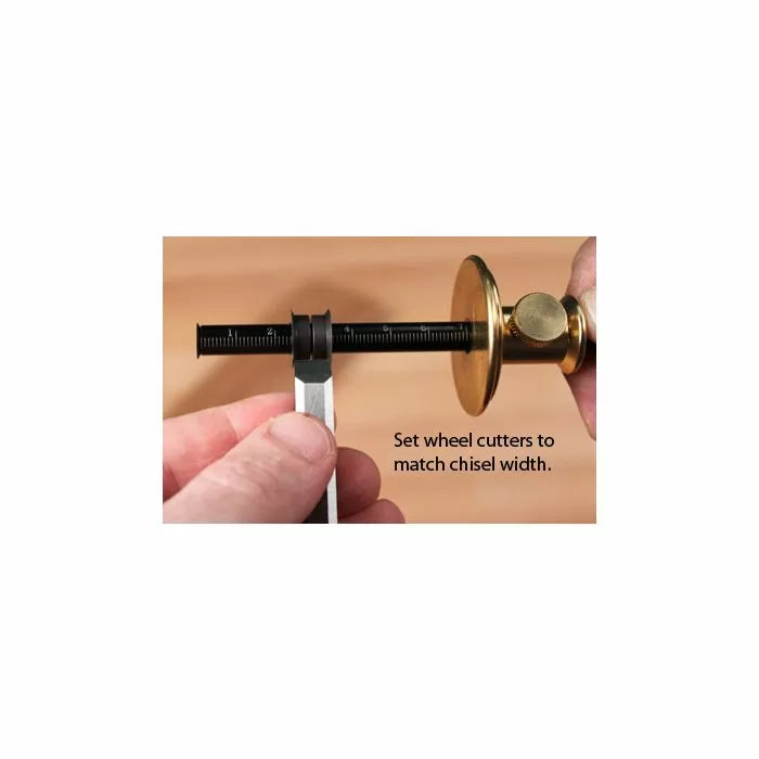 Setting a woodworking wheel marking gauge to match chisel width on a wooden workbench