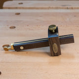 Ebony marking gauge with brass accents on a wooden workbench for precision woodworking
