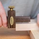 Ebony marking gauge with brass knob used for precise woodworking measurements on wood