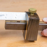 Ebony marking gauge with brass knob and ruler, woodworking layout tool on wood surface