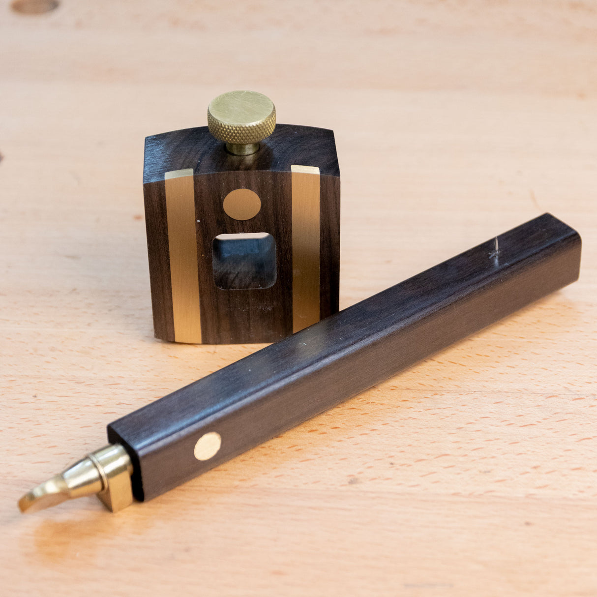 Ebony marking gauge with brass accents on a woodworking bench