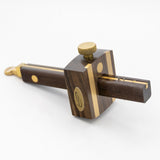 Ebony marking gauge with brass accents for woodworking on a white background
