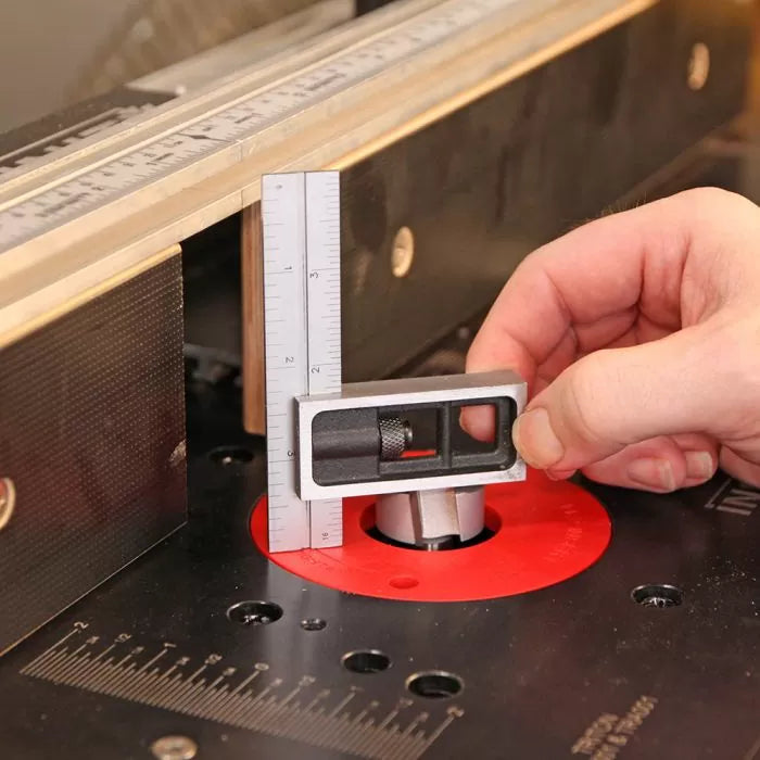 Hand using precision square to measure router bit height on woodworking router table