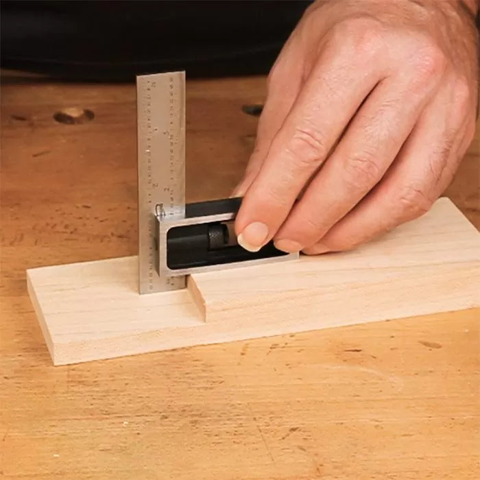 Woodworker using a precision square to measure a wooden joint on a workbench