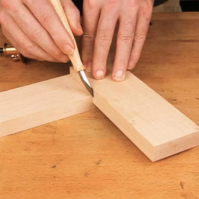 Marking knife scoring wood for precise joinery on a workbench, woodworking hand tool