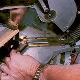 Close-up of miter saw cutting wood with precision measuring jig, woodworking tool in use
