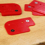 Red plastic woodworking jig templates on a wooden workbench for drilling precise holes.