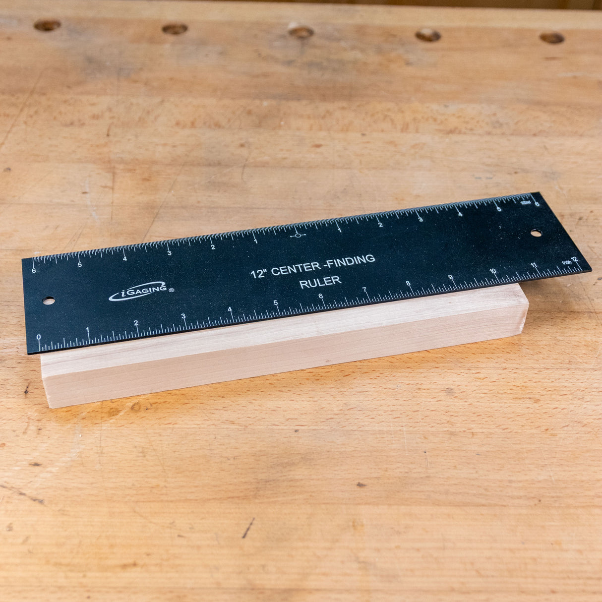 12-inch center-finding ruler measuring a wooden block on a workbench
