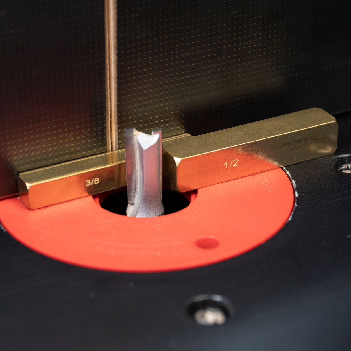 Brass setup bars measuring router bit height on a router table for precise woodworking.