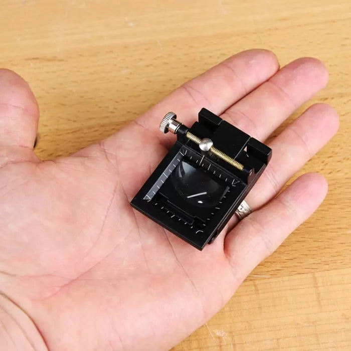 Small woodworking blade sharpening jig with metal screw held in hand on wood surface