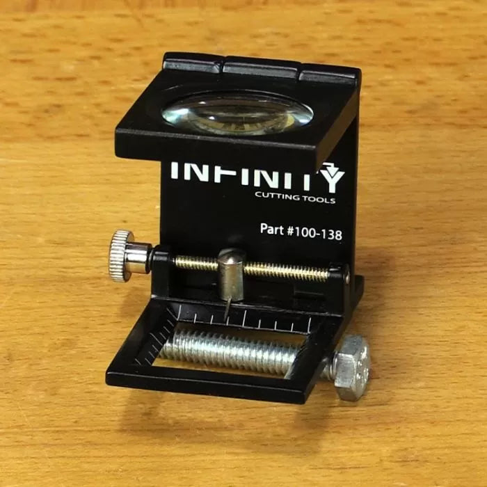 Magnifying edge gauge tool for woodworking on a wood surface, with adjustment screws and ruler markings.