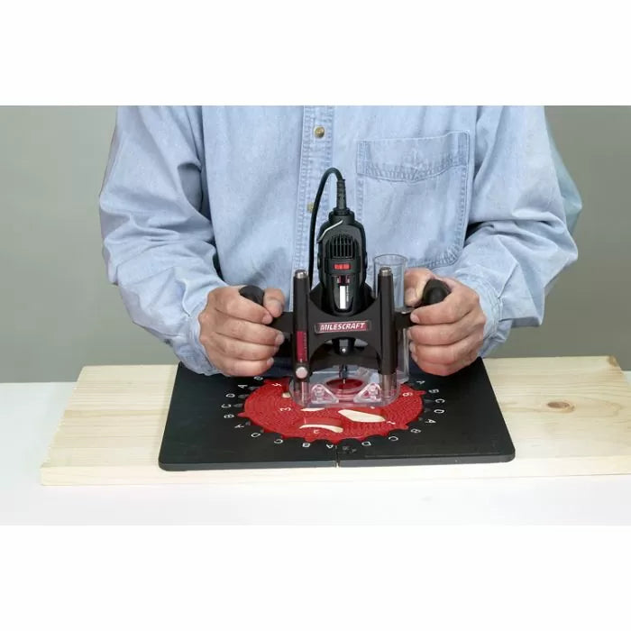 Person using a handheld router on a woodworking template at a workbench