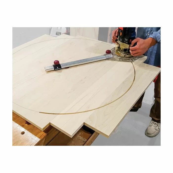 Woodworker using a router circle jig to cut a large arc in a plywood panel on a bench