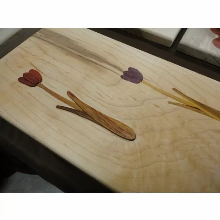 Wood inlay of tulip flowers on a light board, showcasing precision woodworking detail