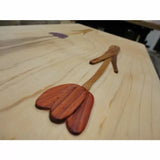 Wood inlay tulip flower design on a light-colored hardwood panel, showcasing fine woodworking.