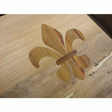 Fleur-de-lis wood inlay detail on a light wood surface, precise woodworking joinery