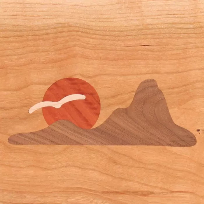 Wood inlay art with mountain, sun, and bird motif on light maple panel