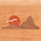 Wood inlay art with mountain, sun, and bird motif on light maple panel