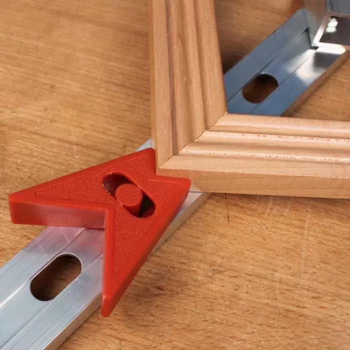 Woodworking corner clamp with red plastic angle and frame on workbench