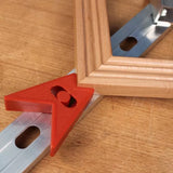Woodworking corner clamp with red plastic angle and frame on workbench