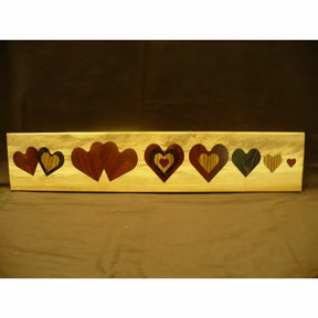 Woodworking inlay project with multiple heart-shaped patterns on a rectangular wood board
