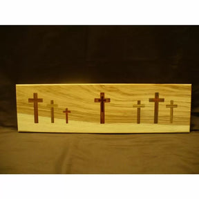 Decorative wooden plaque with multiple inlaid cross designs on natural wood background.