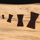 Close-up of four wooden bow tie inlays in light wood slab for woodworking joinery repair.