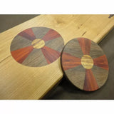 Wood inlay disc with segmented design in contrasting hardwoods on a light wooden board