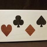Wood inlay of heart, club, diamond, and spade suit symbols on a light wood panel