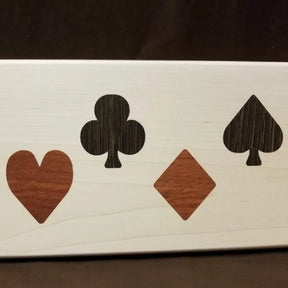 Wood inlay of heart, club, diamond, and spade suit symbols on a light wood panel