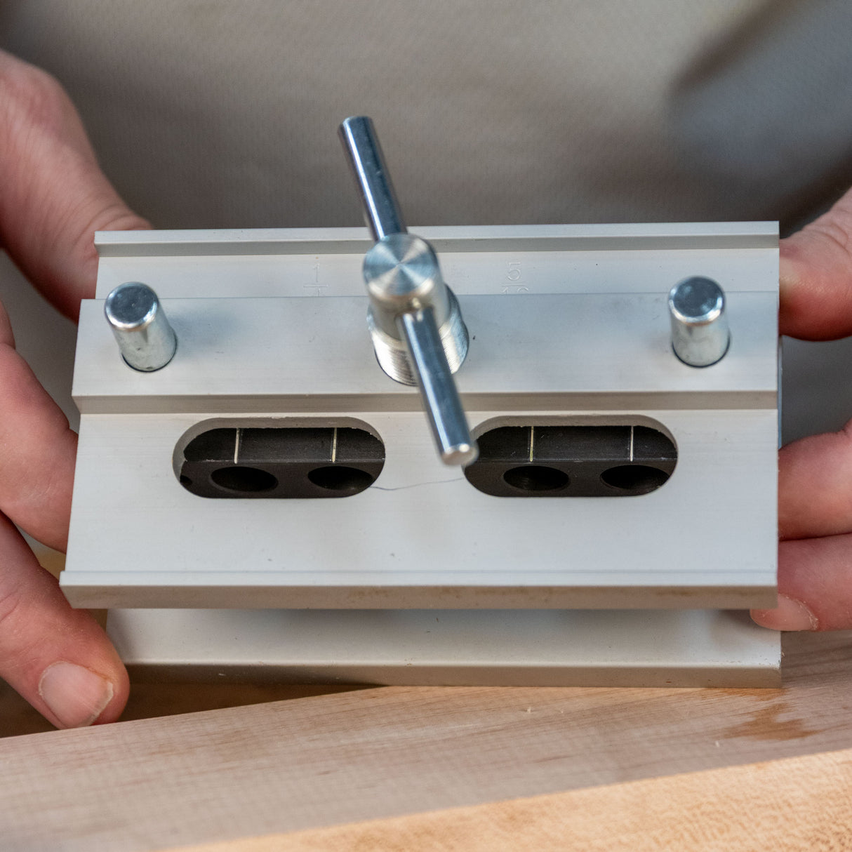 Self-centering dowel jig for woodworking clamped to a wooden board