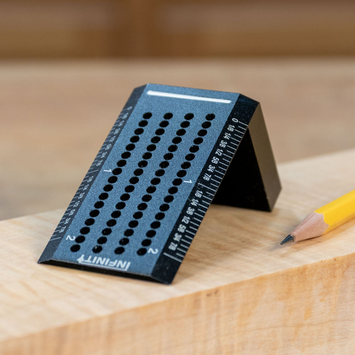 Black woodworking saddle square with measuring holes and marked ruler edges on a workbench