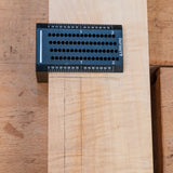 Precision woodworking saddle square in use marking lines on a wood board.